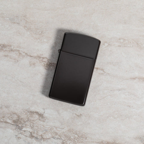 Lifestyle image of Slim® Brown Windproof Lighter laying on a marble surface
