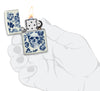 Zippo lighter glows in the dark skull with crown surrounded by blue flowers opened with flame in stylised hand