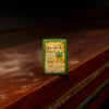 Lifestyle image of Cannabis Design Moss Green Matte Windproof Lighter standing on a wooden bar