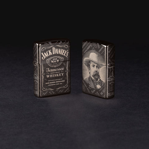 Lifestyle image of two Jack Daniel's® Photo Image 360® Black Ice® Windproof Lighters standing in a black background. One lighter is showing the front and the other is showing the back.