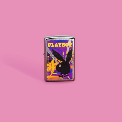 Lifestyle image of Playboy Beach Rabbit Head Street Chrome™ Windproof Lighter standing in a pink background.
