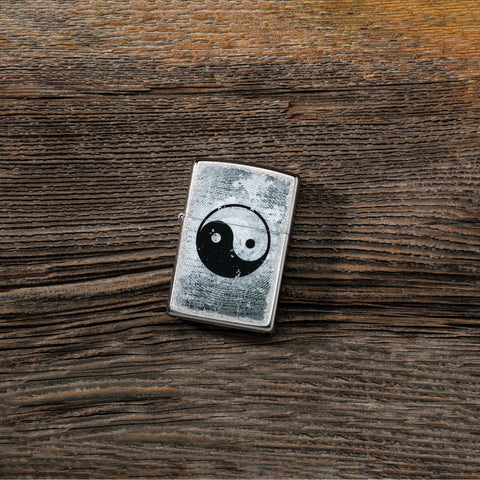 Lifestyle image of Yin Yang Design Street Chrome™ Windproof Lighter laying on a wooden table.