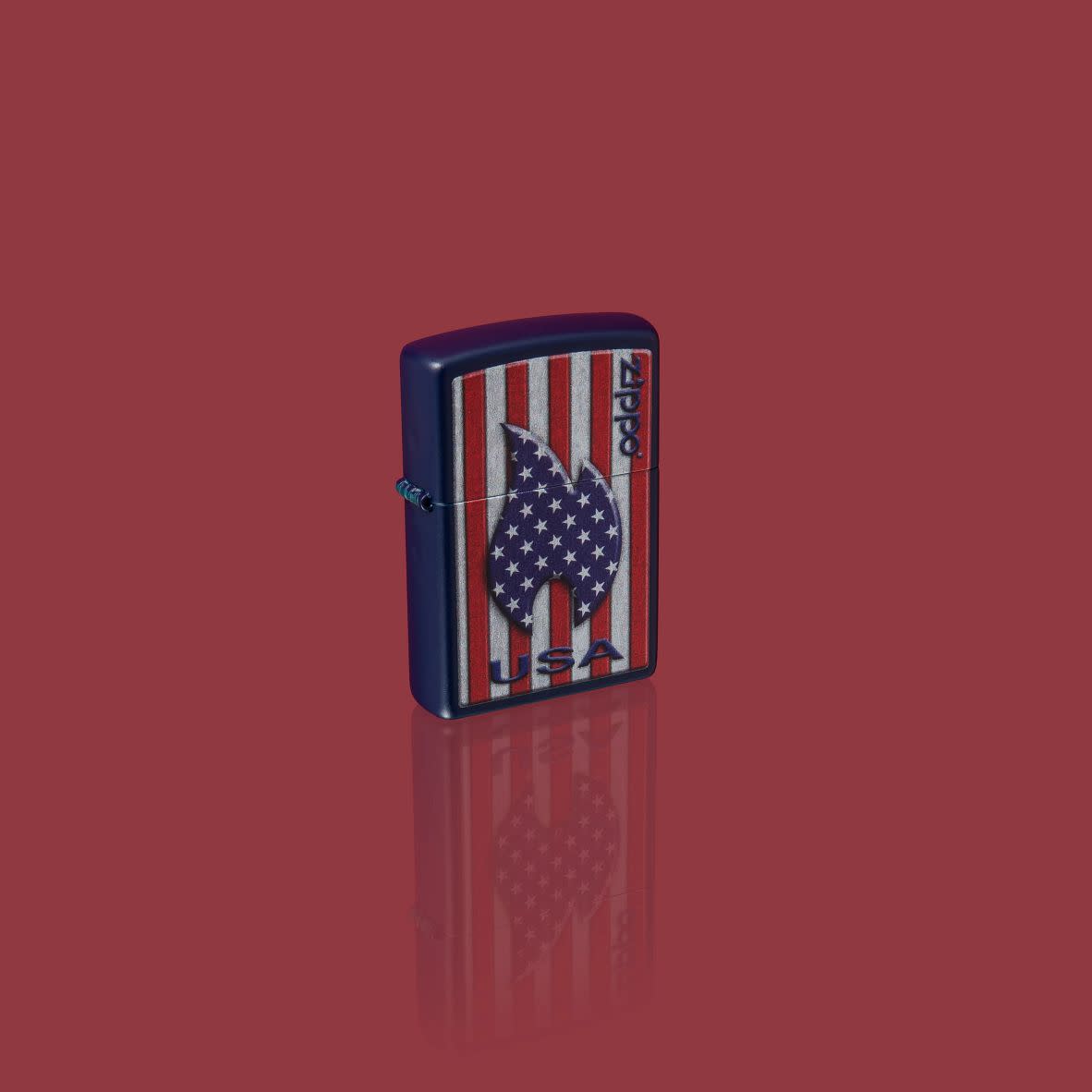 Glamour shot of Zippo Patriotic Flame Design Navy Matte Windproof Lighter standing in a red scene.