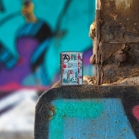 Lifestyle image of Anarchy Design Street Chrome™ Windproof Lighter, standing in a street with graffiti. 