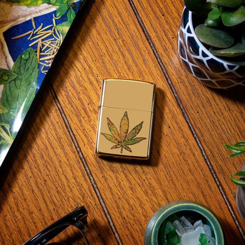 Lifestyle image of Pot Leaf Fusion Design Windproof Lighter laying on a wooden side stand