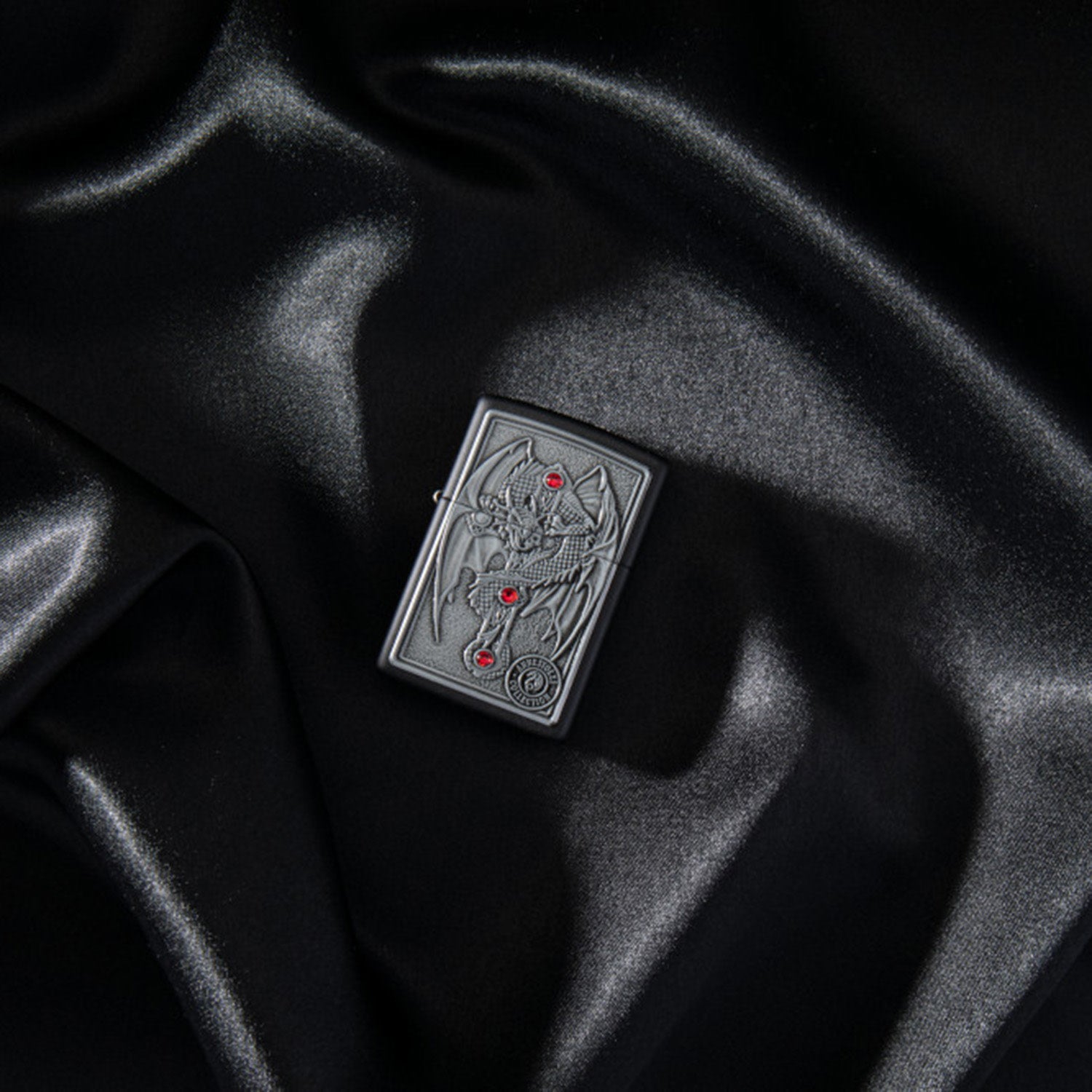 Lifestyle image of Anne Stokes Gothic Guardian Emblem Black Matte Windproof Lighter laying in a black scene.