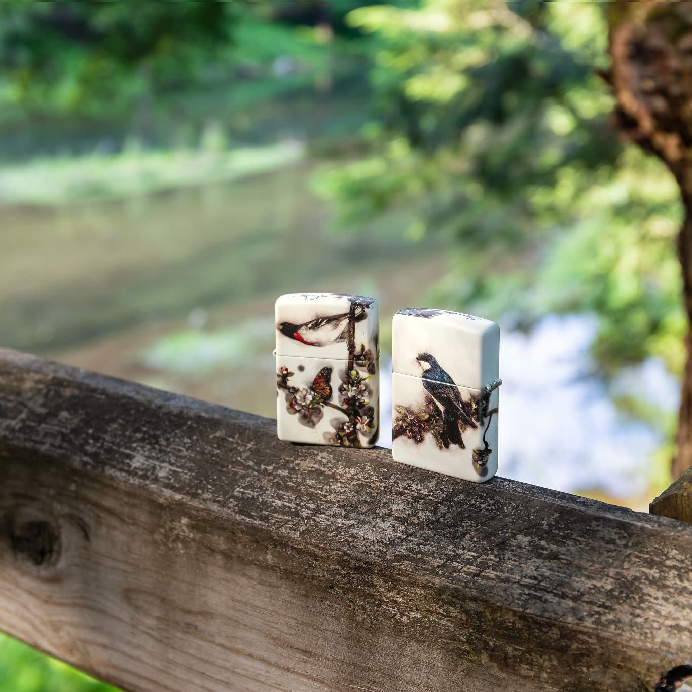 Lifestyle image of two Spazuk Fire Art 540 Color Windproof Lighters standing on a railing outside with water in the background.