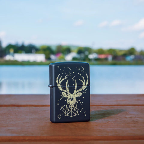 Lifestyle image of Deer Constellation Design Black Matte Windproof Lighter standing on a railing with a lake behind it.